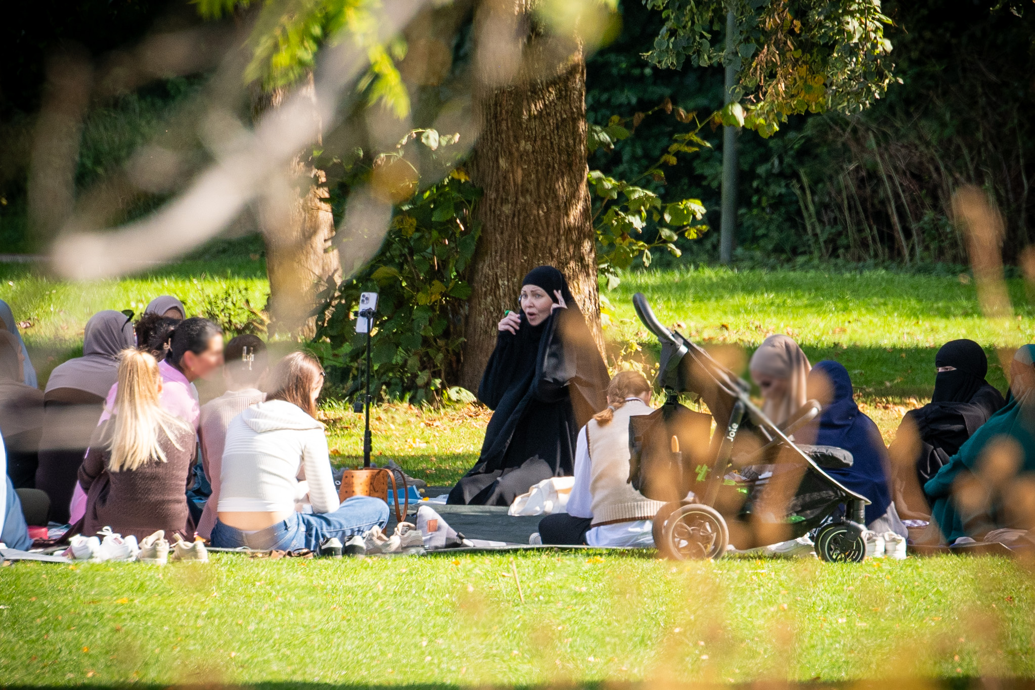 Das Foto zeigt das Picknick im Westpark. Frauen und Kinder sitzen auf der Wiese. „Hanna Hansen“, schwarz gekleidet, in der Bildmitte.
